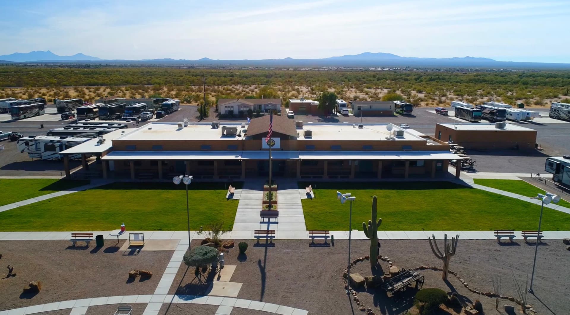 Aerial of the Tucson Trap & Skeet clubhouse, central courtyard and flagpole, with the RV park and Tucson-area mountains beyond.